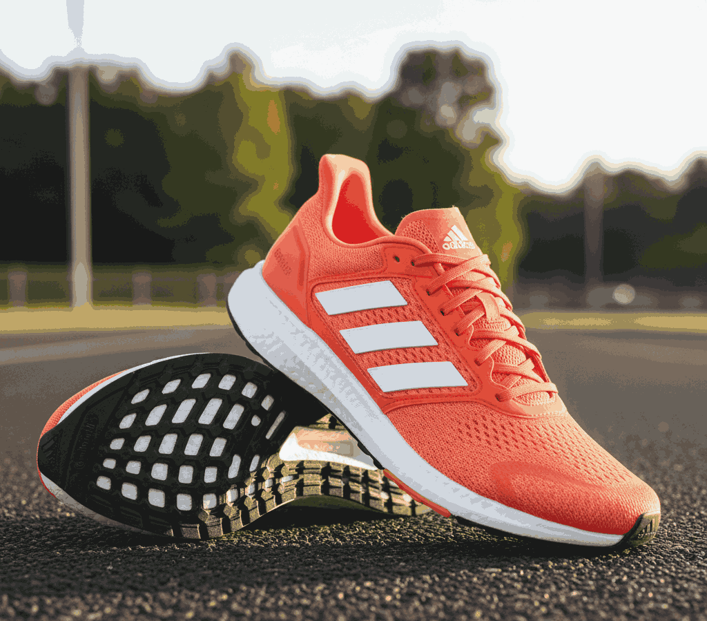 Orange Adidas running shoes with white stripes and black sole outdoors