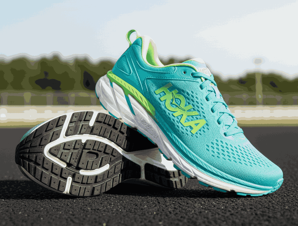 Turquoise Hoka running shoes with green accents and chunky white sole on outdoor track