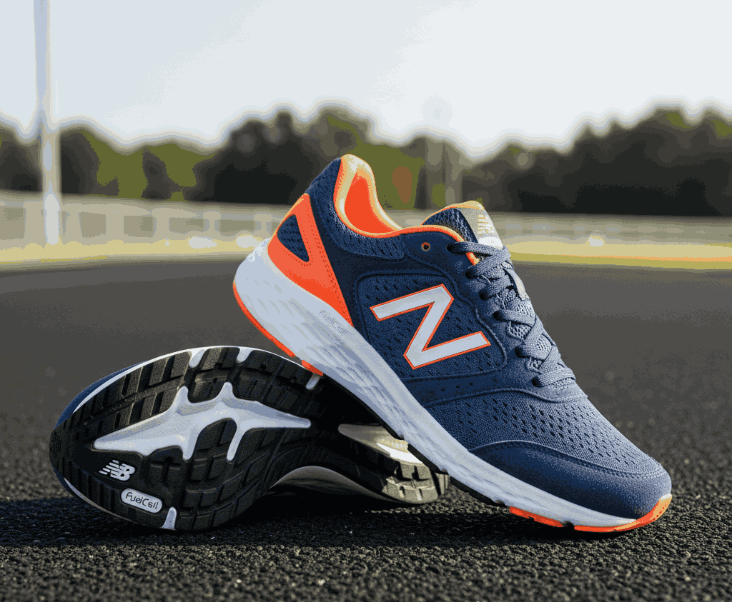 Navy blue New Balance running shoes with orange accents and white sole on outdoor track
